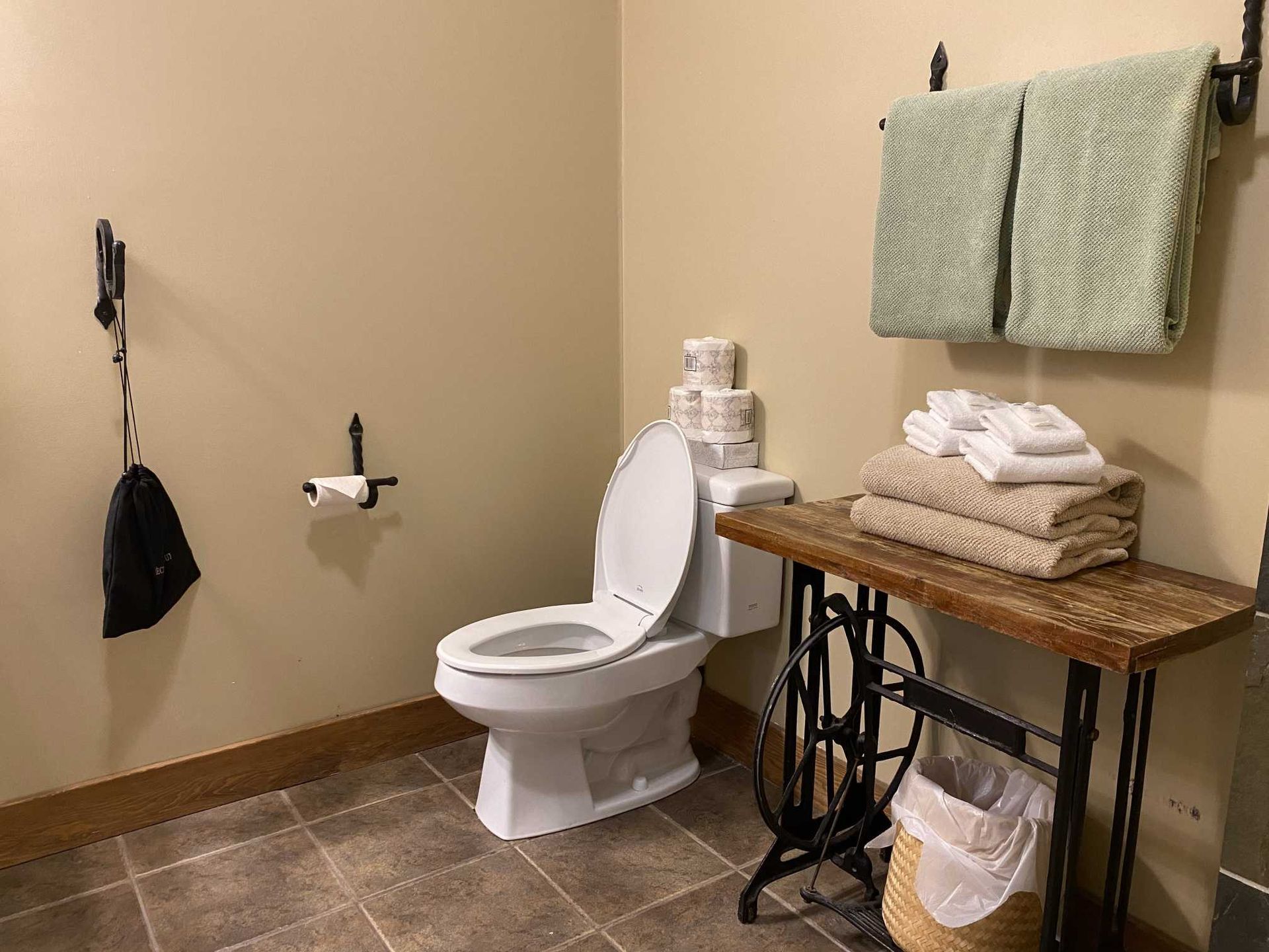 A bathroom with a toilet , towels , and a sewing machine.