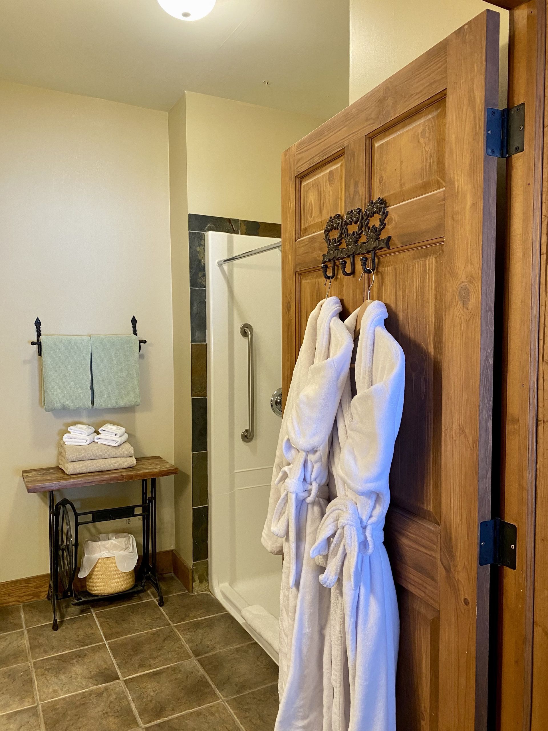 Two bathrobes are hanging on a wooden door in a bathroom.