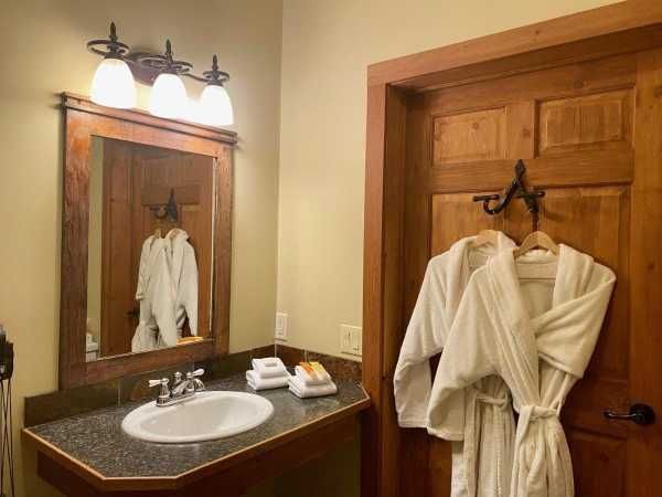 A bathroom with robes hanging on the door and a sink