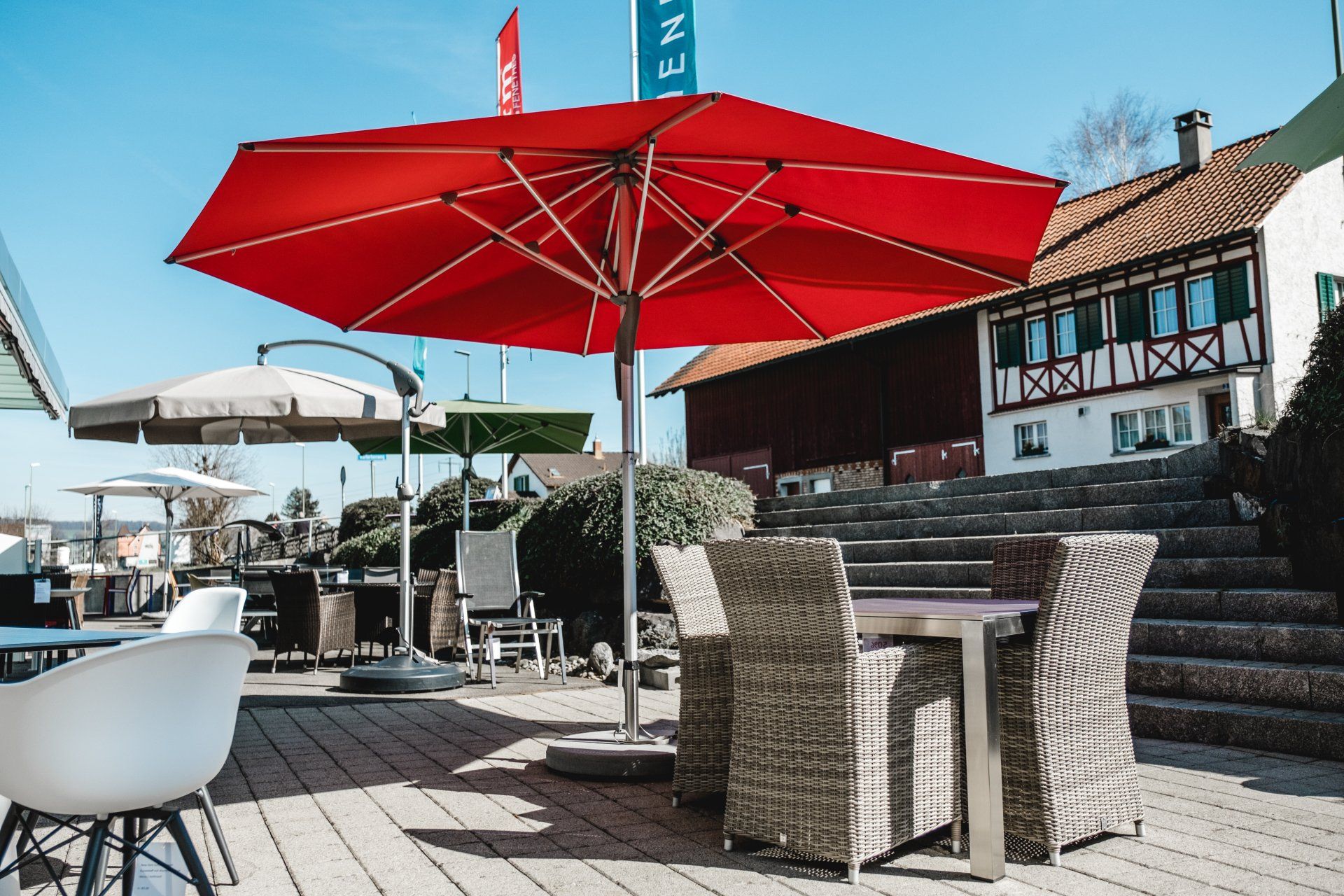 Auf einem Holzdeck steht ein grosser roter Sonnenschirm.
