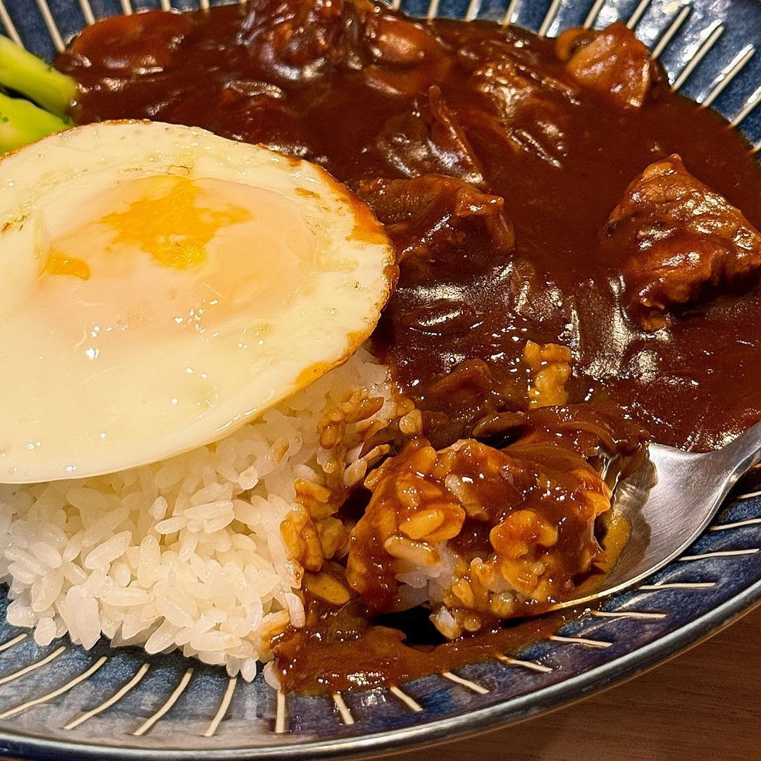 A close up of a plate of food with rice and a fried egg on a table.