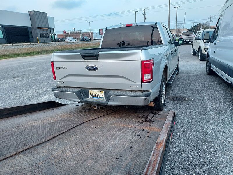 A silver ford truck is parked on the side of the road.