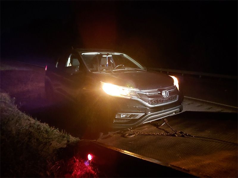 A car is sitting on the side of the road at night.