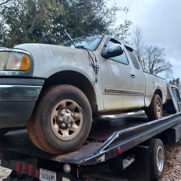 A white truck is sitting on top of a tow truck