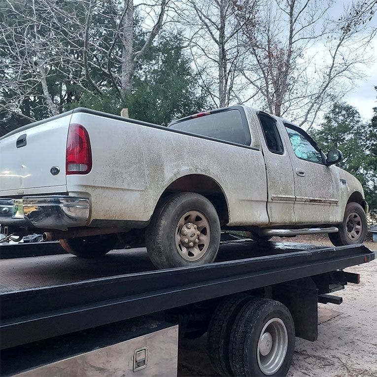 A white truck is sitting on top of a tow truck.