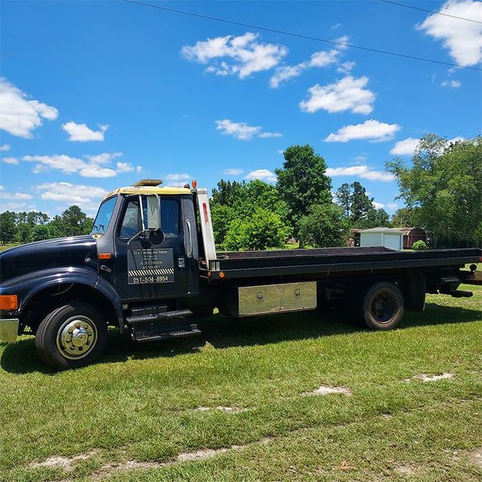 A black tow truck is parked in a grassy field.