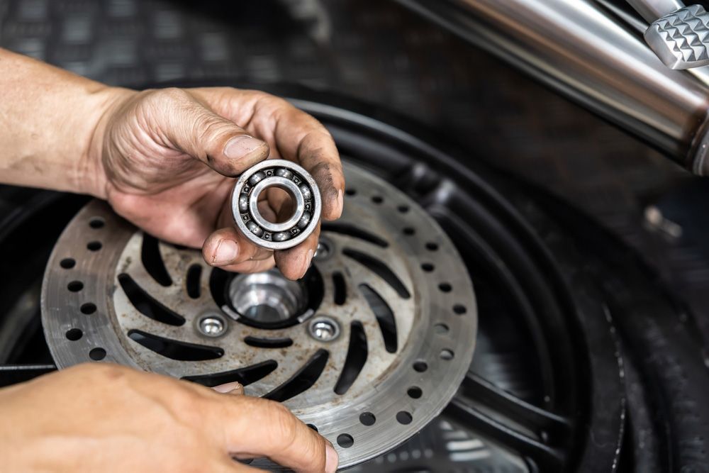 A person is holding a bearing over a brake disc on a motorcycle.