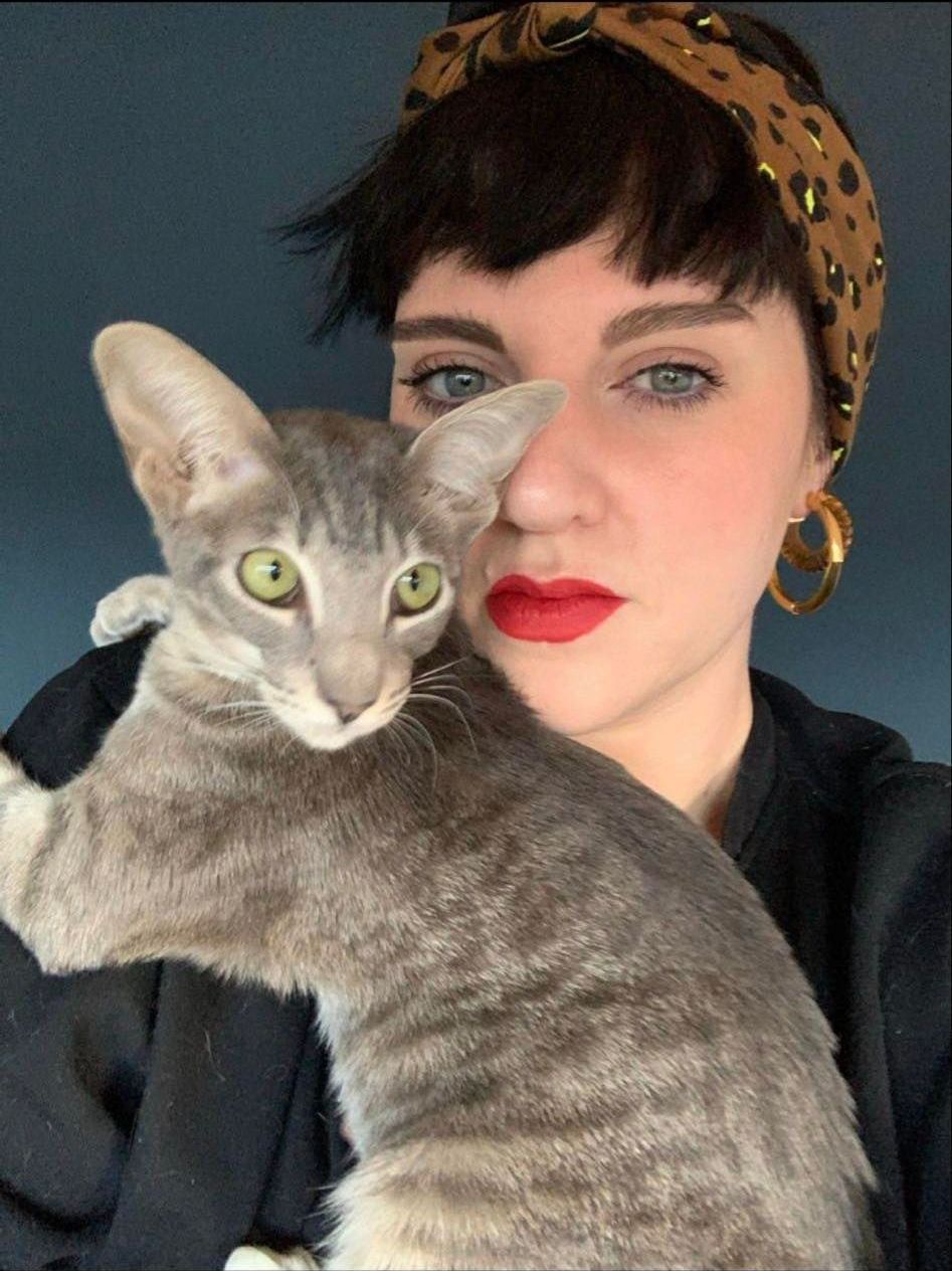 A woman wearing a headband is holding a cat