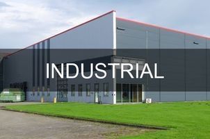 Industrial building with a black and silver exterior; a grassy lawn in front.