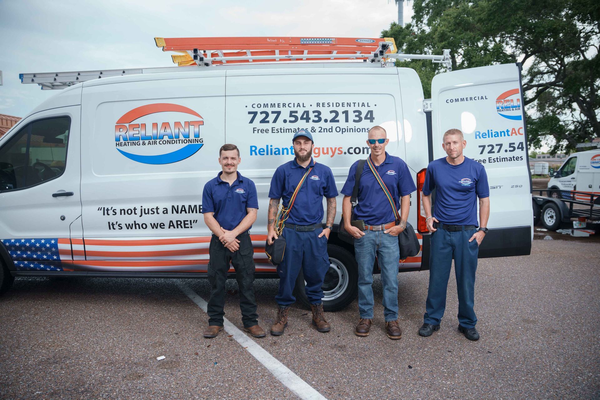 A group of Reliant Heating & Air Conditioning technician are standing in front of a van.