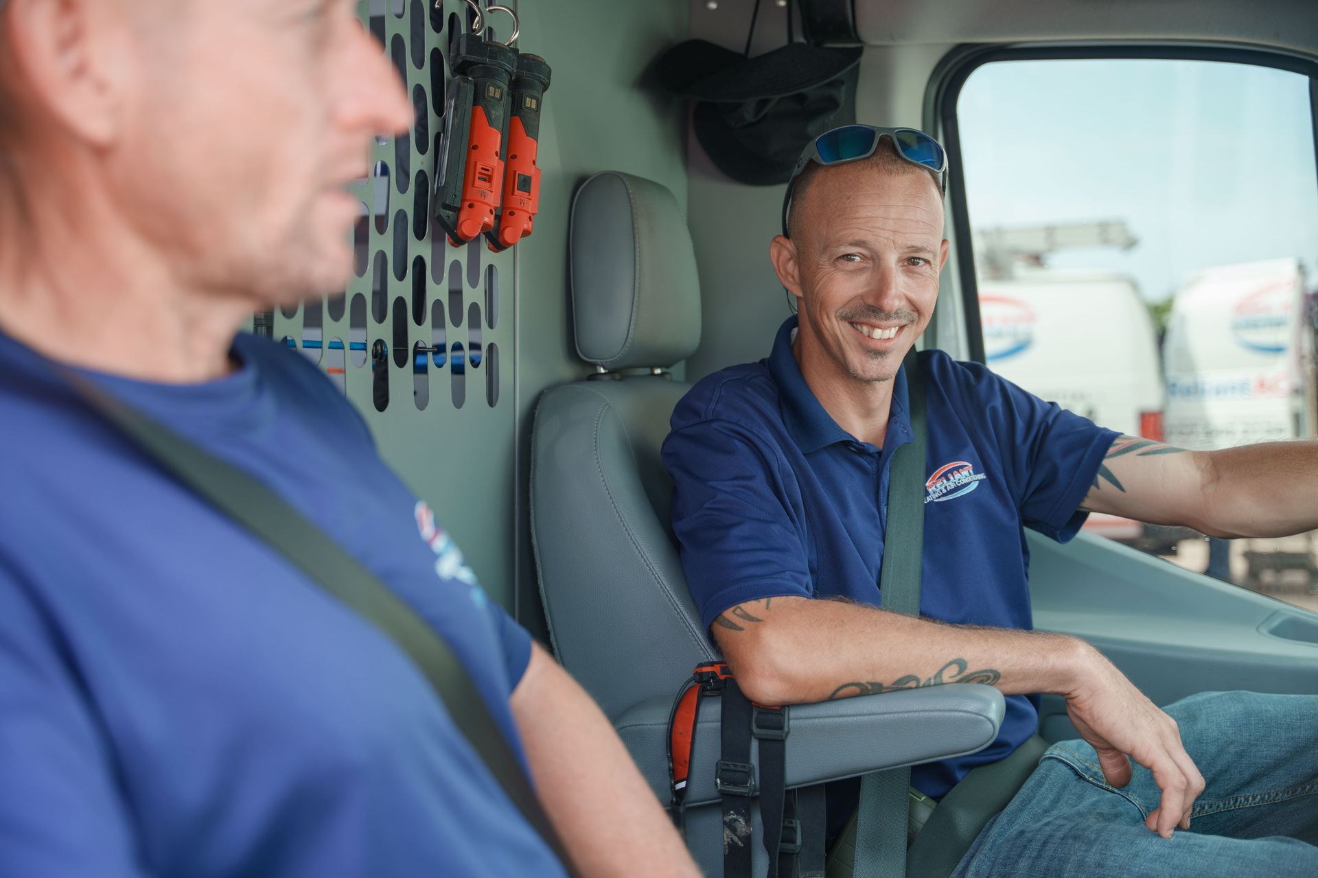 Two Reliant Heating & Air Conditioning technician are sitting in the back seat of a van.