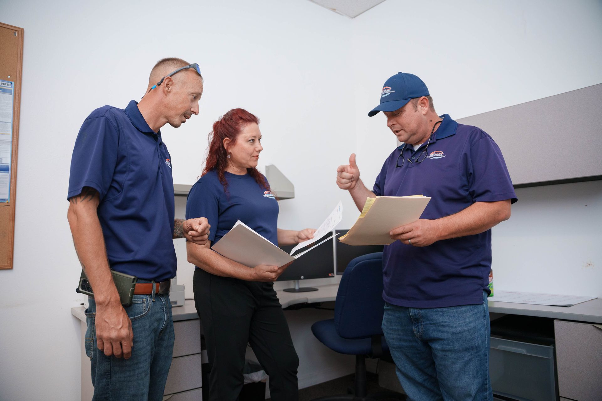 Reliant Heating & Air Conditioning technicians are standing in an office looking at papers.
