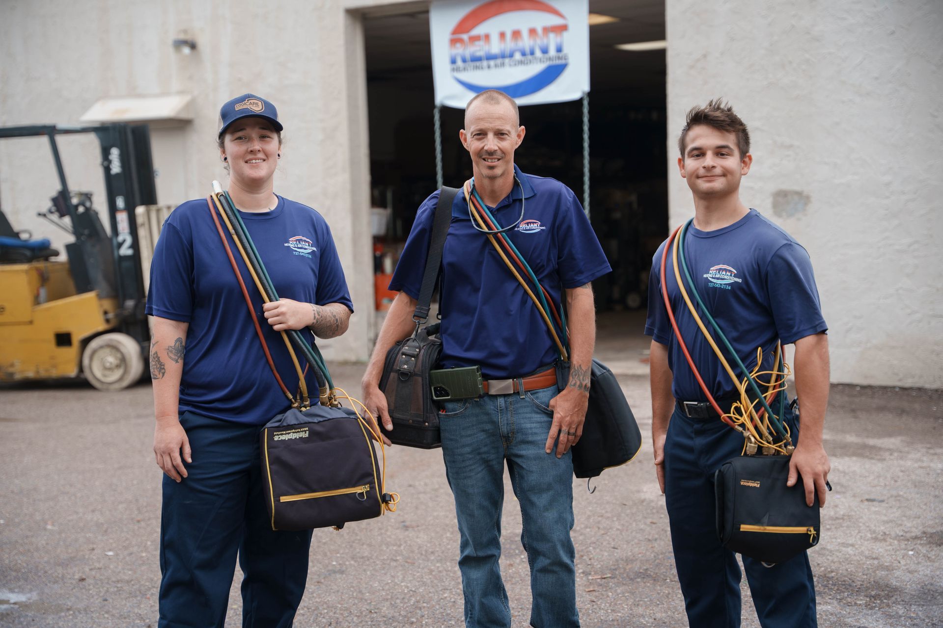 Three Reliant Heating & Air Conditioning technician standing in front of a pepsi sign