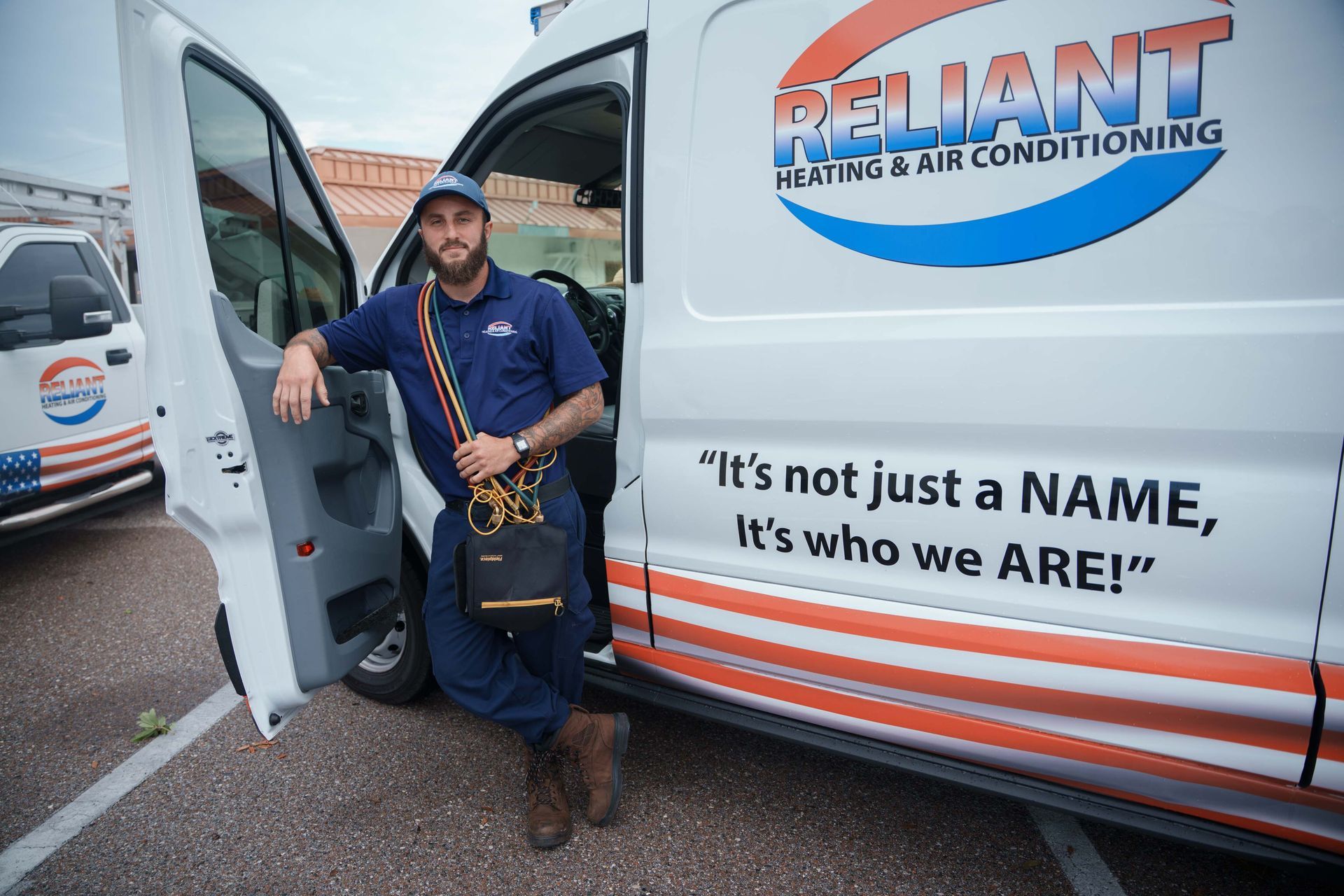 A Reliant Heating & Air Conditioning technician is standing in front of a reliant heating and air conditioning van.
