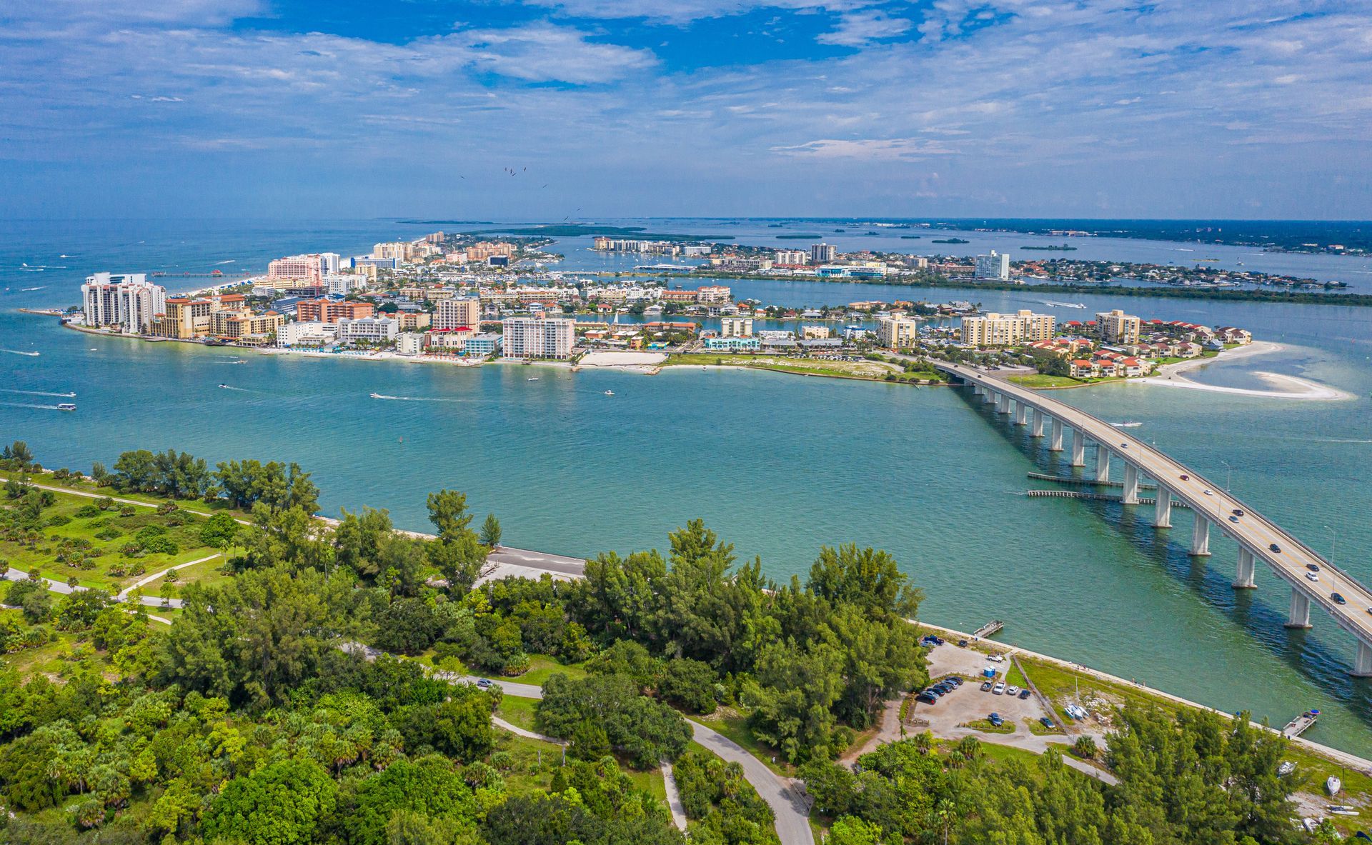 An aerial view of a bridge over a body of water with a city in the background.