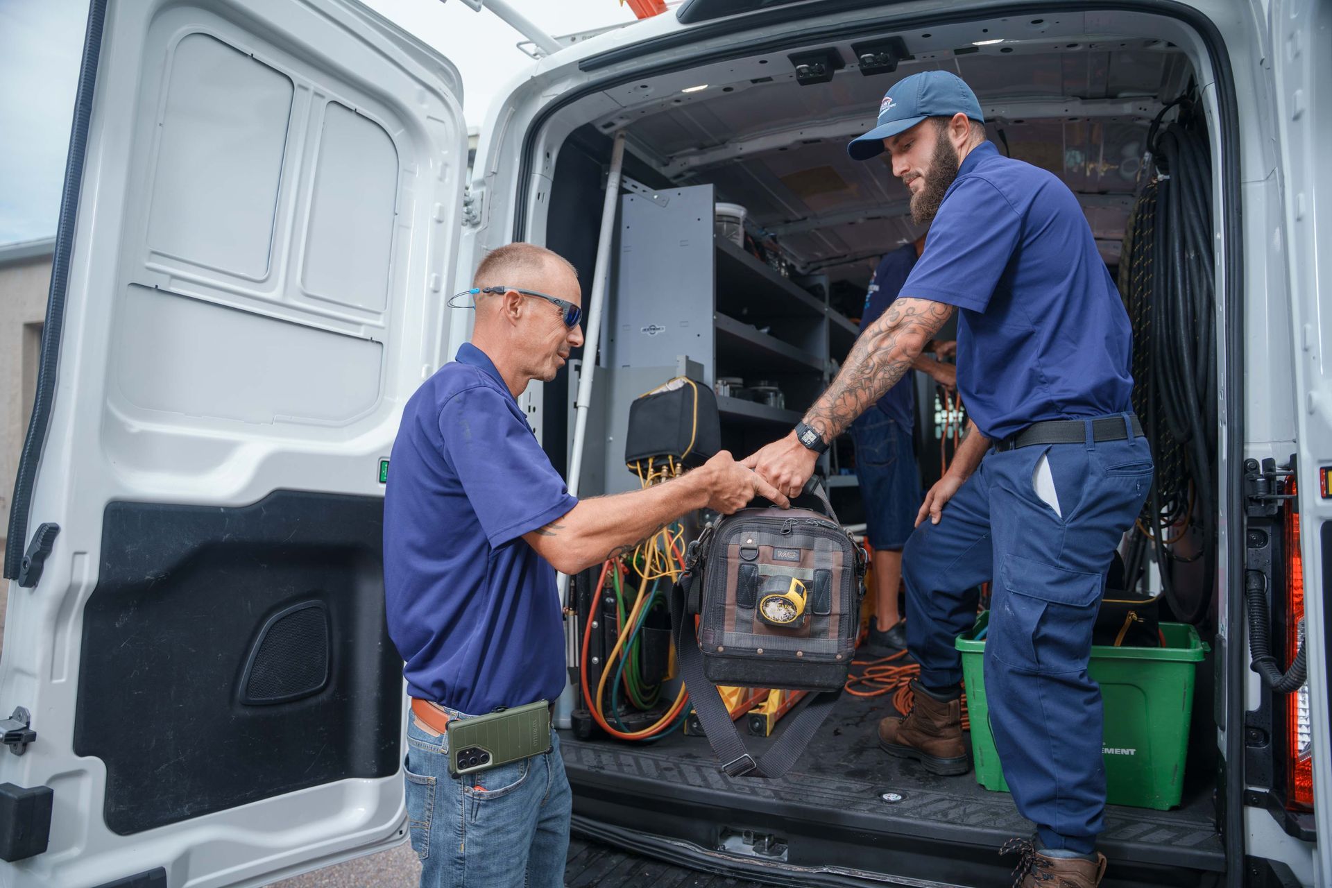 Two Reliant Heating & Air Conditioning technician are shaking hands in front of a van.