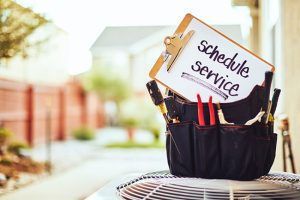 A clipboard with the words `` schedule service '' on it is sitting on top of an air conditioner.