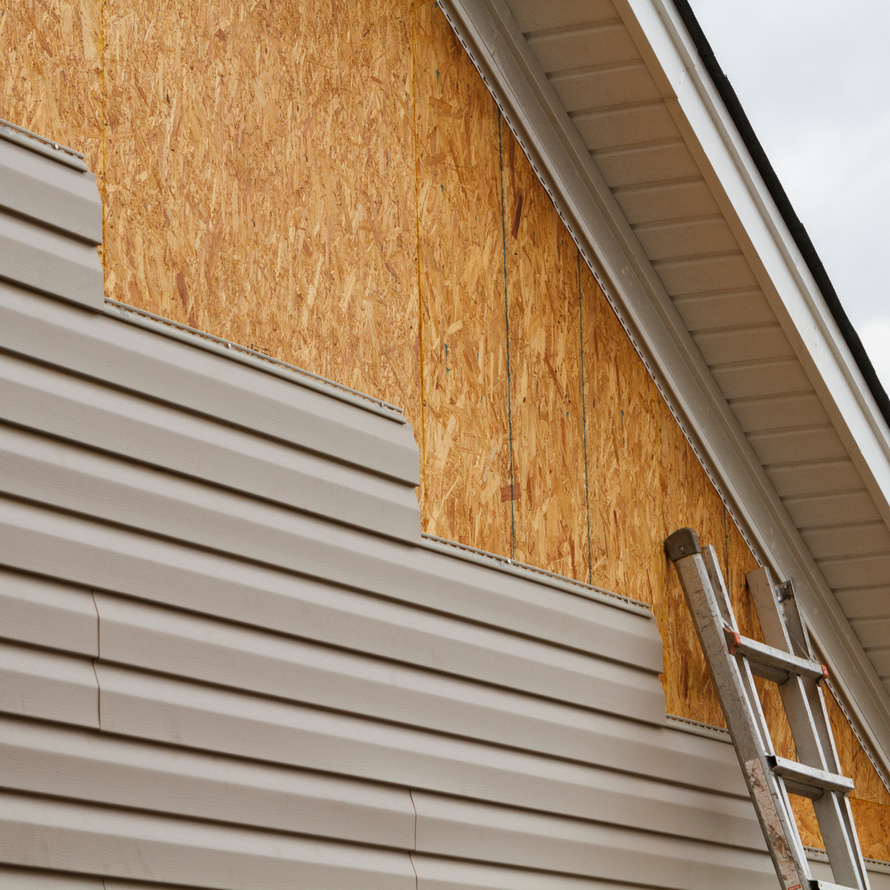 House siding partially removed, showing wood siding and ladder.