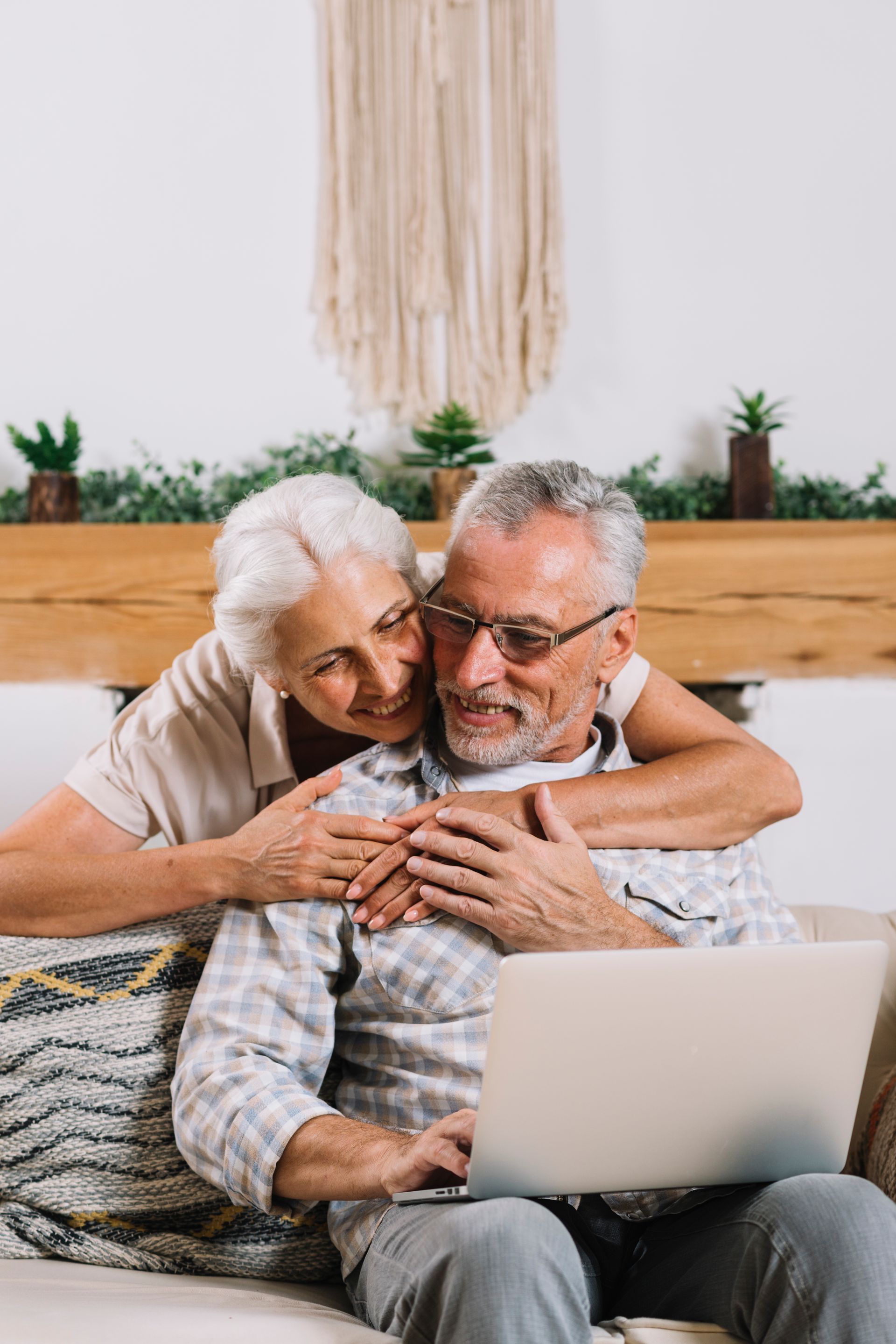 Older couple embracing while looking at a laptop computer.