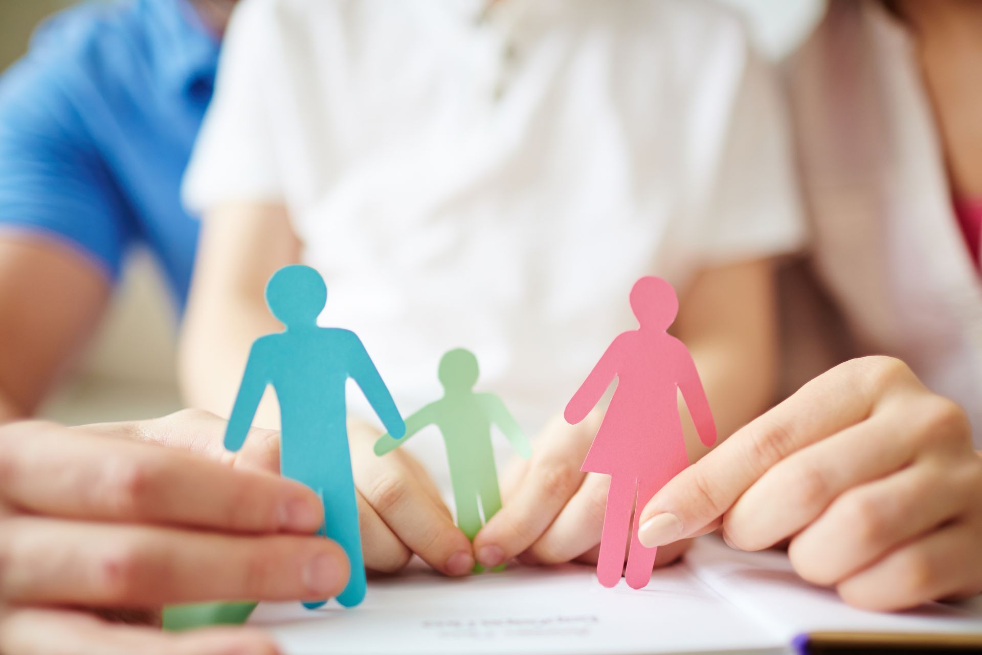 Hands holding paper cutouts of a family; a parent and child.