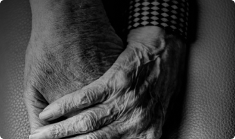 Close-up of two hands gently clasped, one resting over the other in black and white.