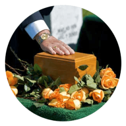 Hand resting on a wooden casket surrounded by orange roses