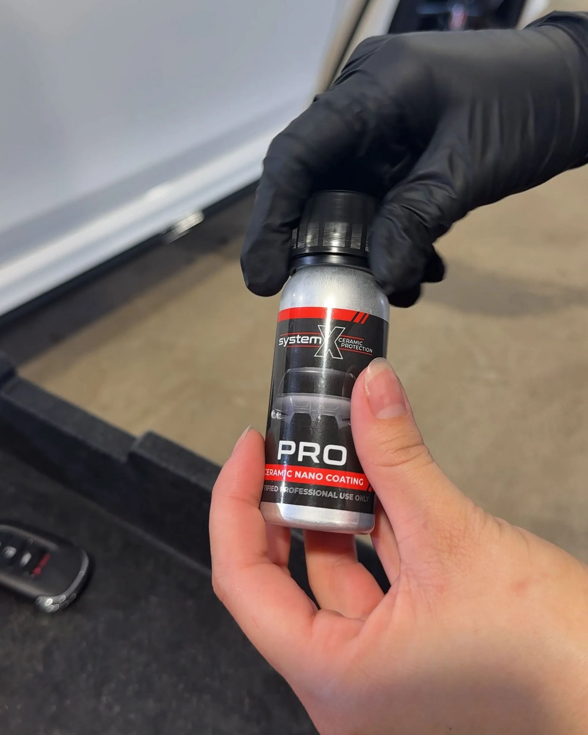 Gloved hands hold a small silver bottle labeled 