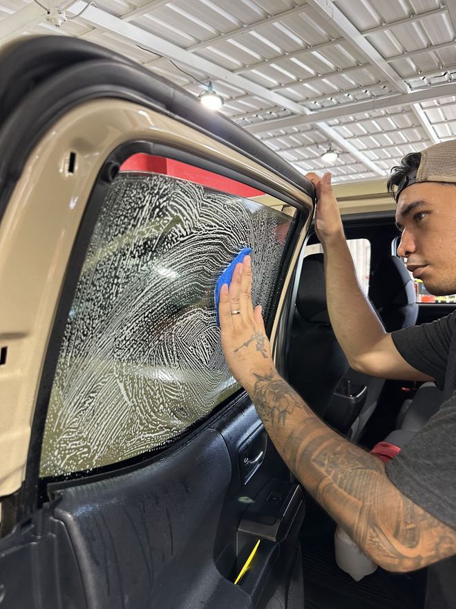 A person is applying a clear film to the hood of a car.