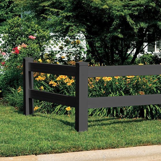 Black fence in front of lush green yard with yellow and red flowers.