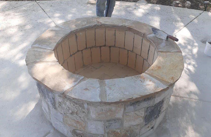 Stone fire pit under construction; person standing nearby.