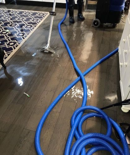 A vacuum cleaner is being used to clean a wooden floor.