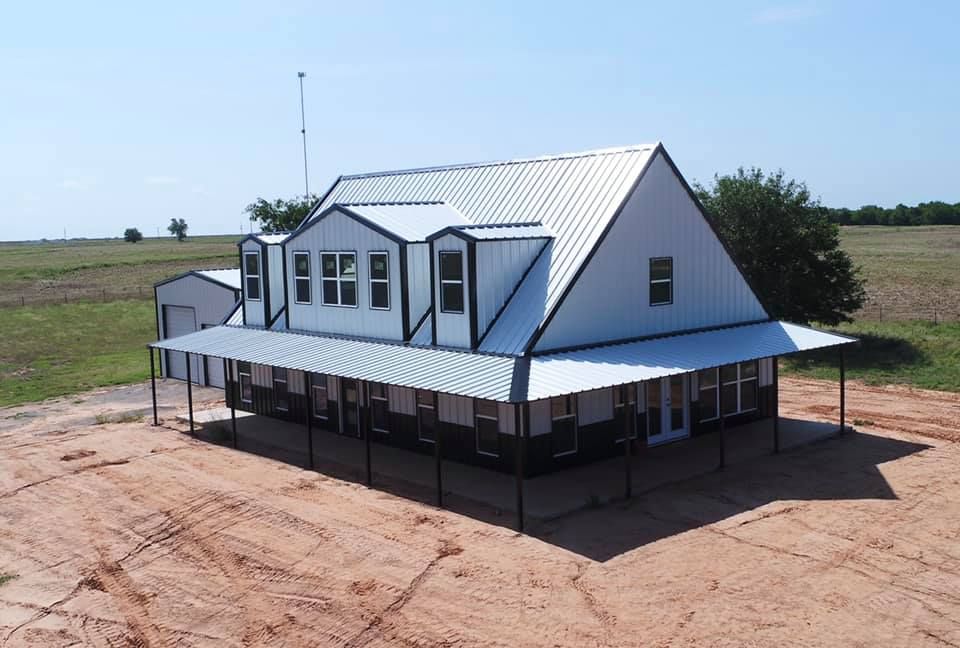 An aerial view of a white house with a metal roof