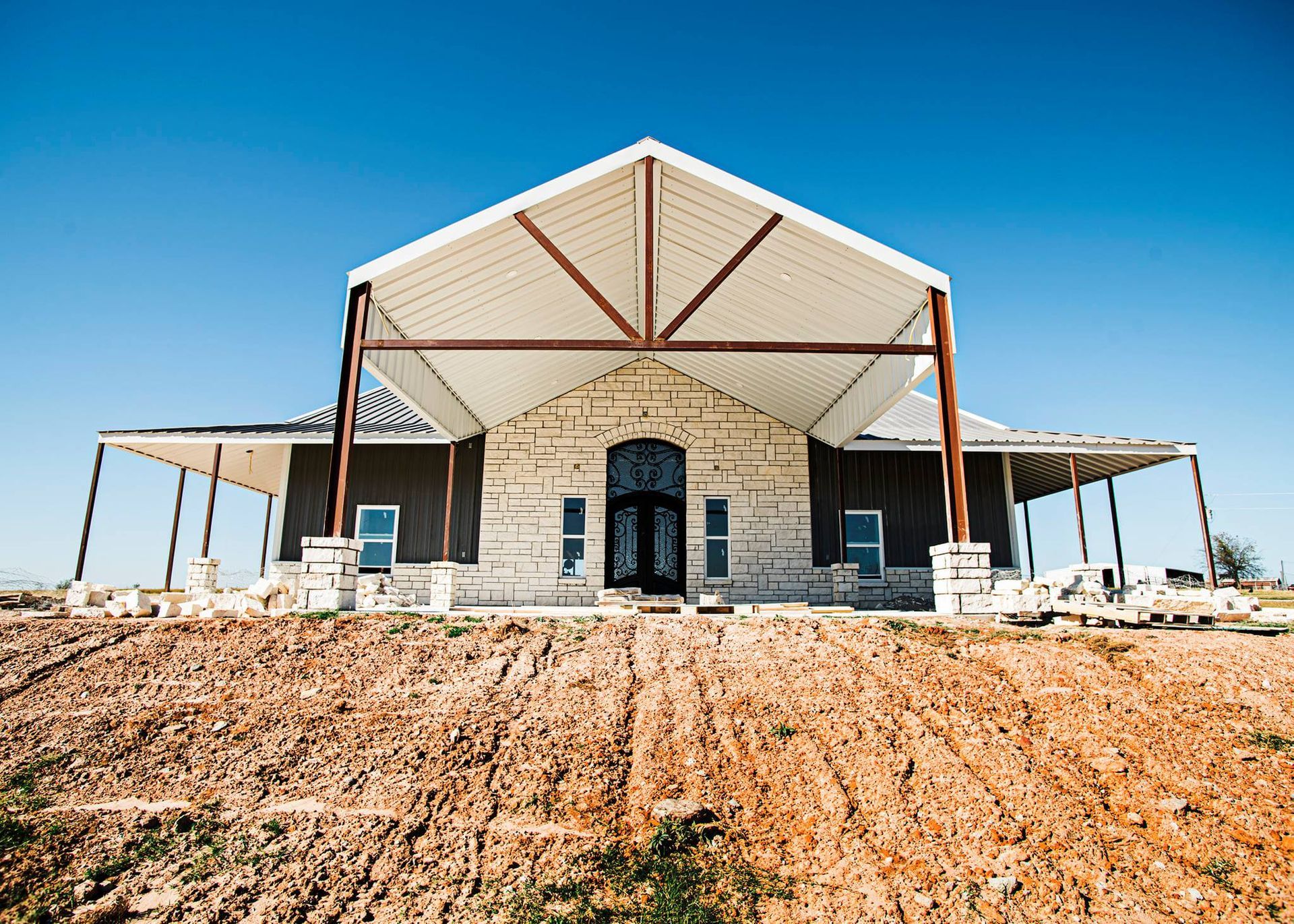A large house is sitting on top of a dirt hill.