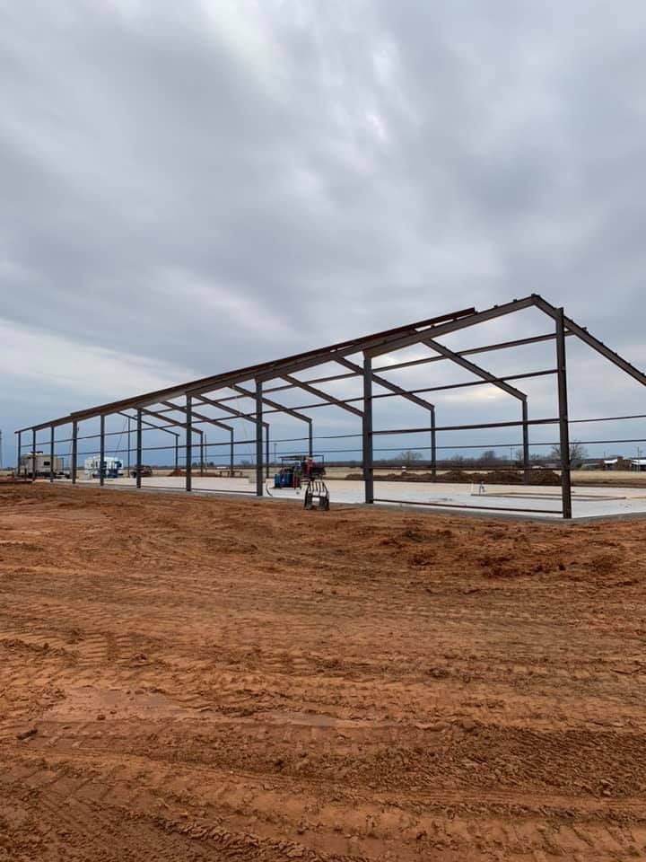 A large metal structure is being built in a dirt field.