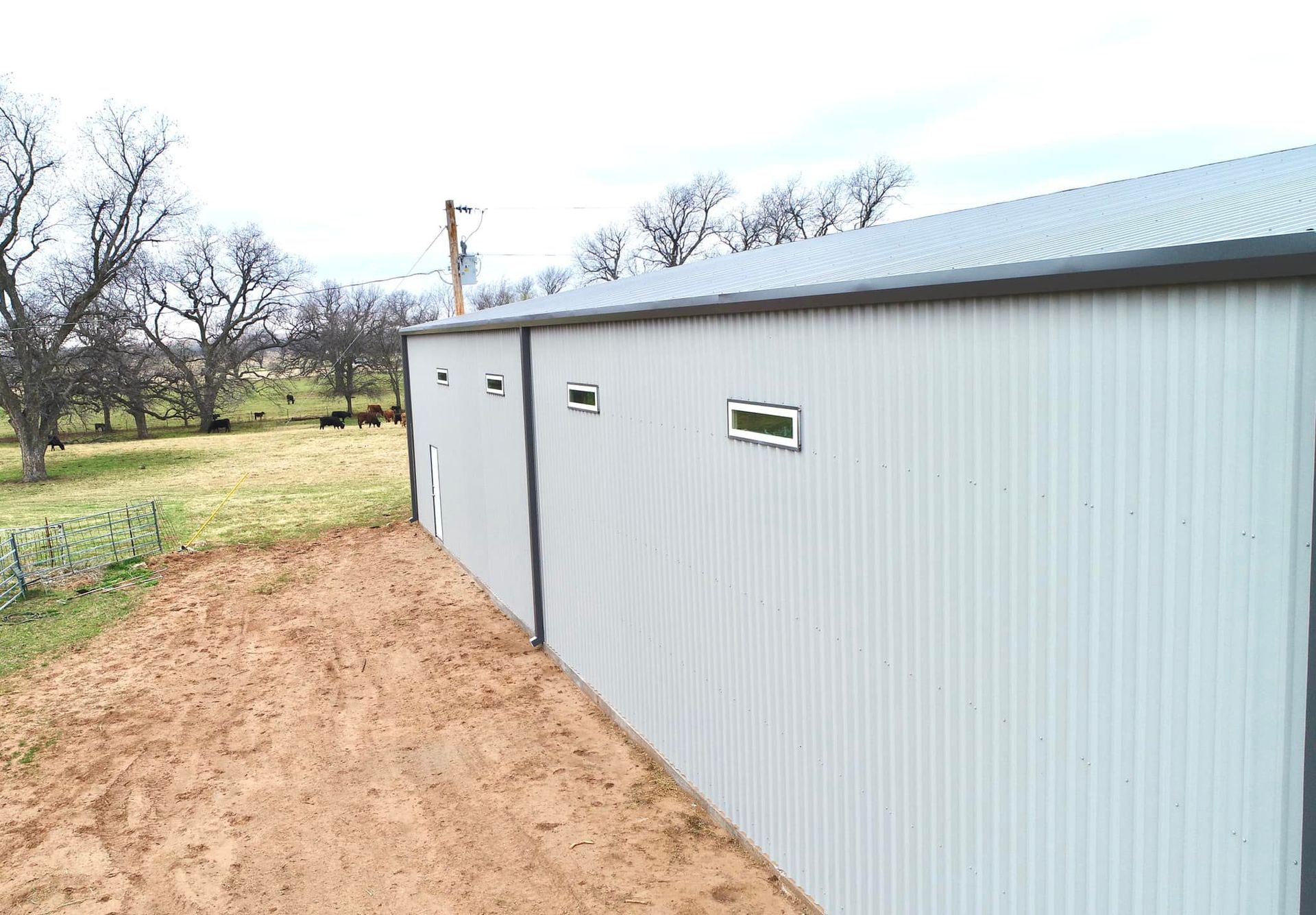 A large metal building with a dirt road leading to it.