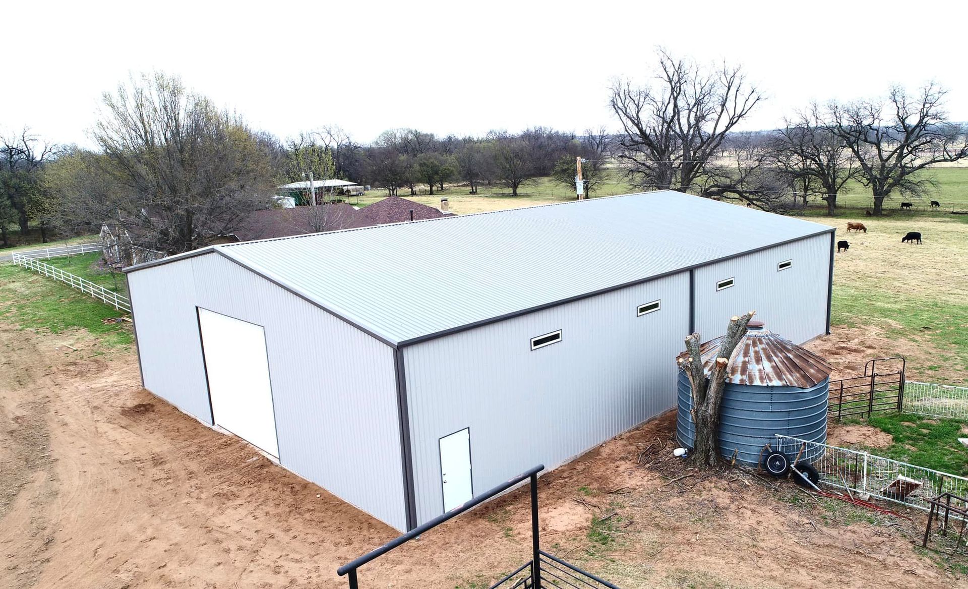 An aerial view of a large metal building in the middle of a field.