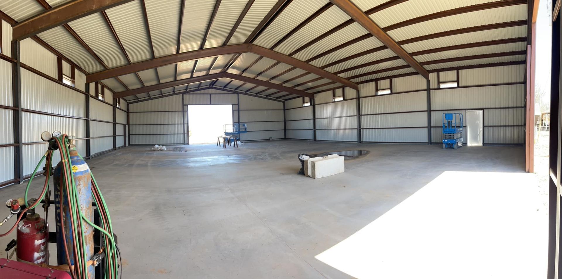 A large empty warehouse with a large door and a fire extinguisher.