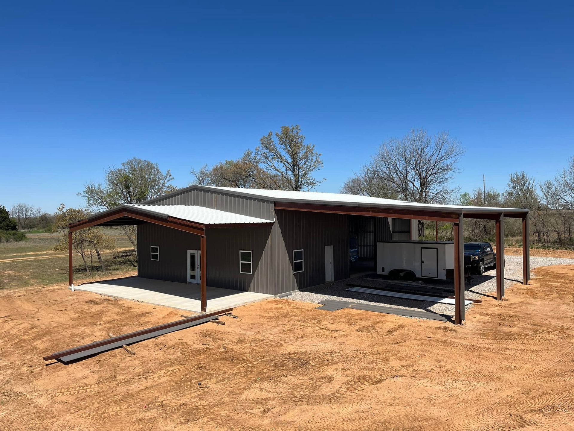A metal building with a covered area and a truck parked in front of it.