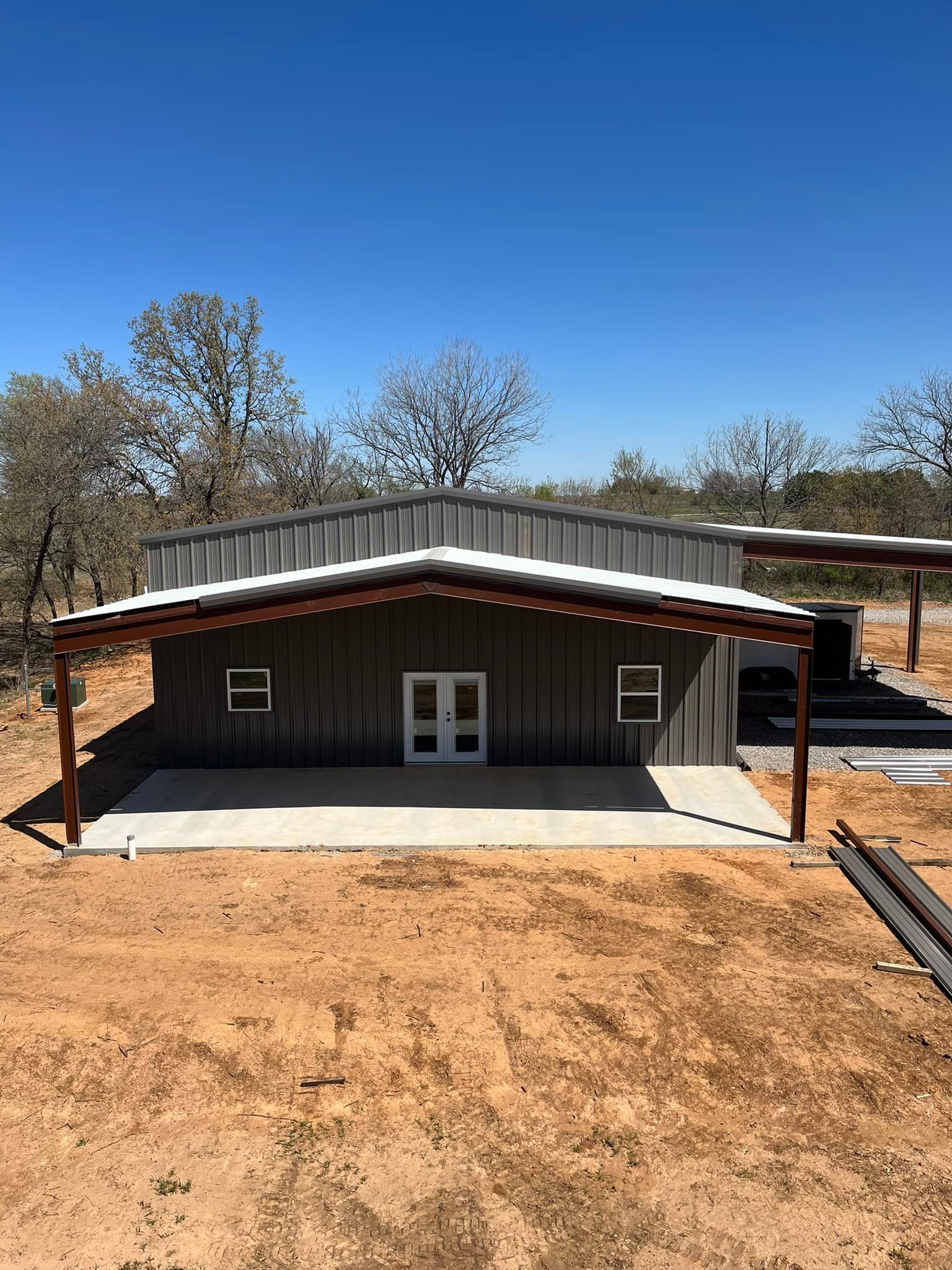 A metal building with a porch in the middle of a dirt field.