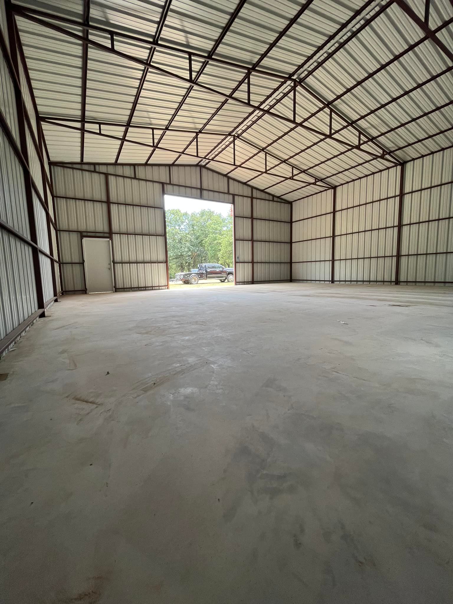 A large empty warehouse with a truck parked in the background.