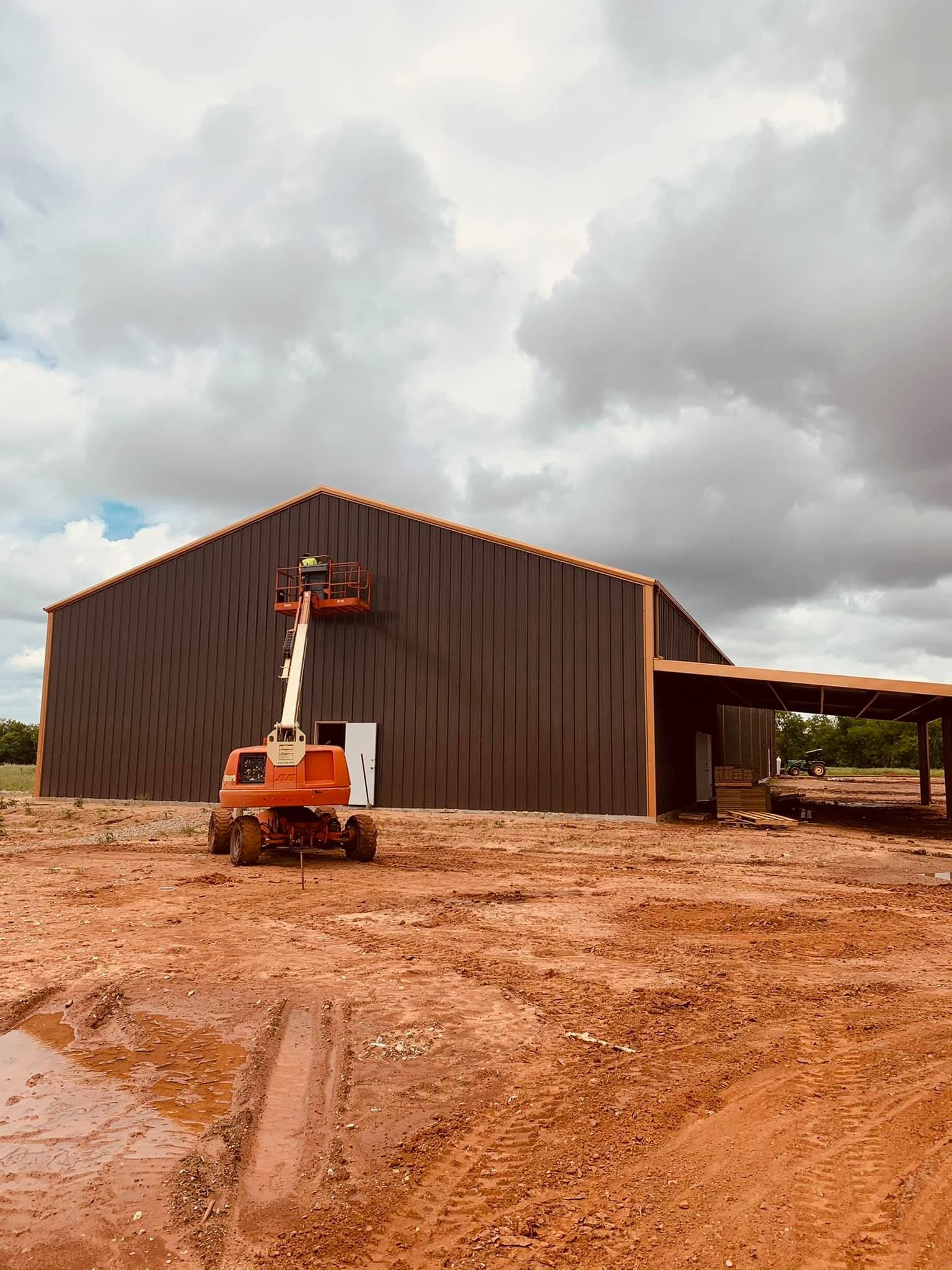 A large building is being built in the middle of a dirt field.