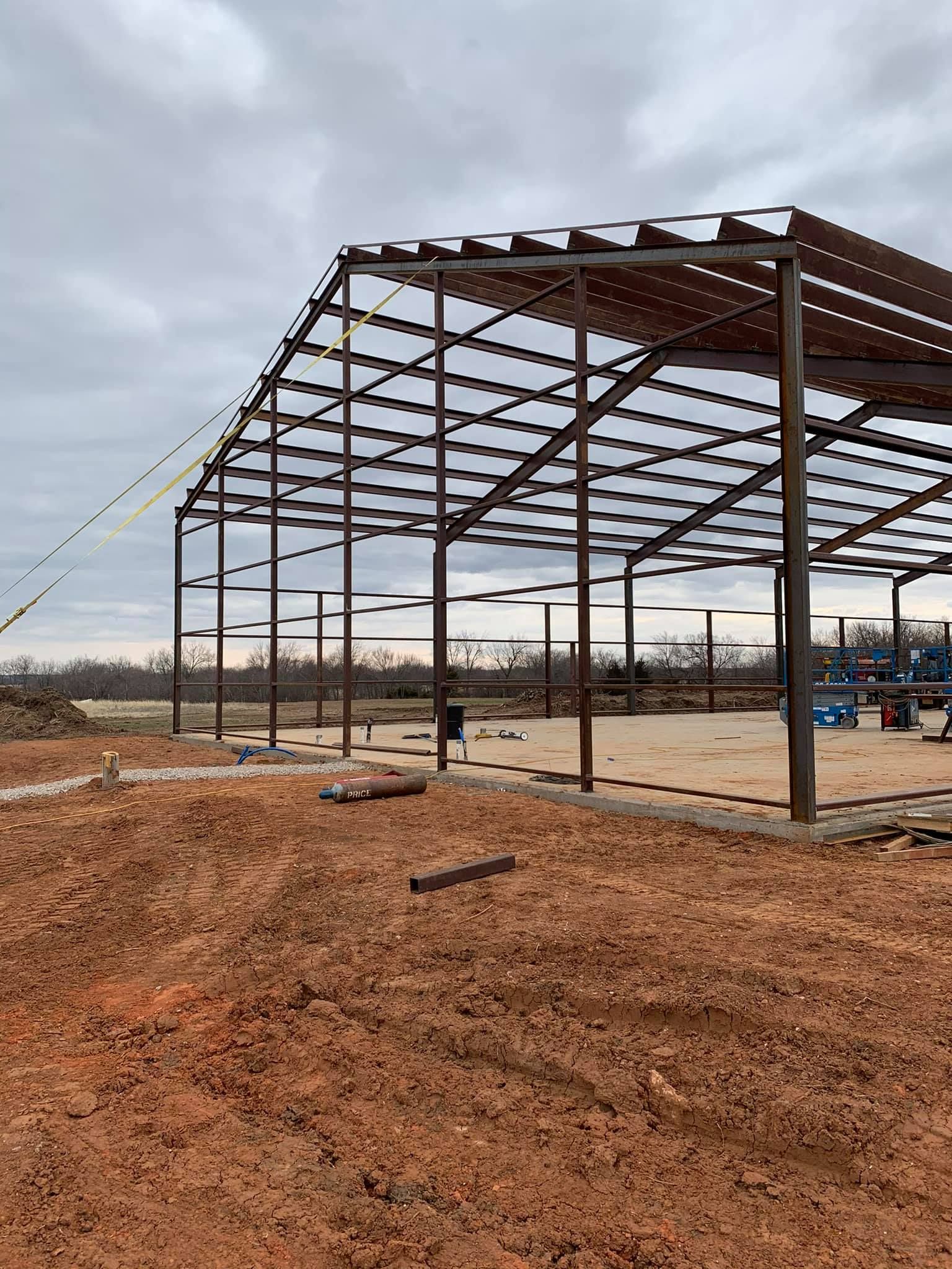 A large metal structure is being built in a dirt field.