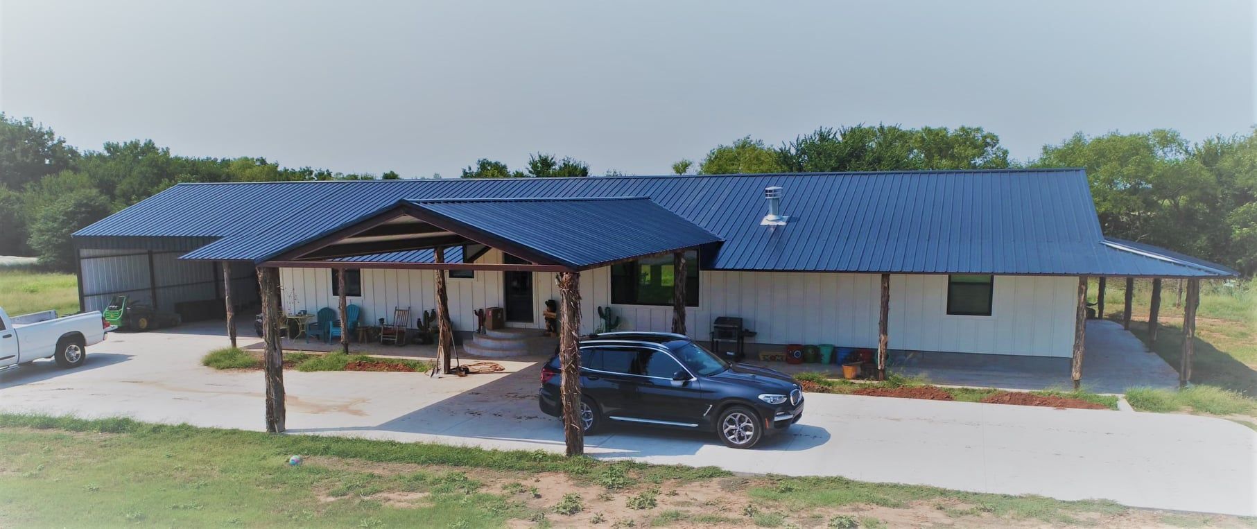 A black suv is parked in front of a large white house with a blue roof.