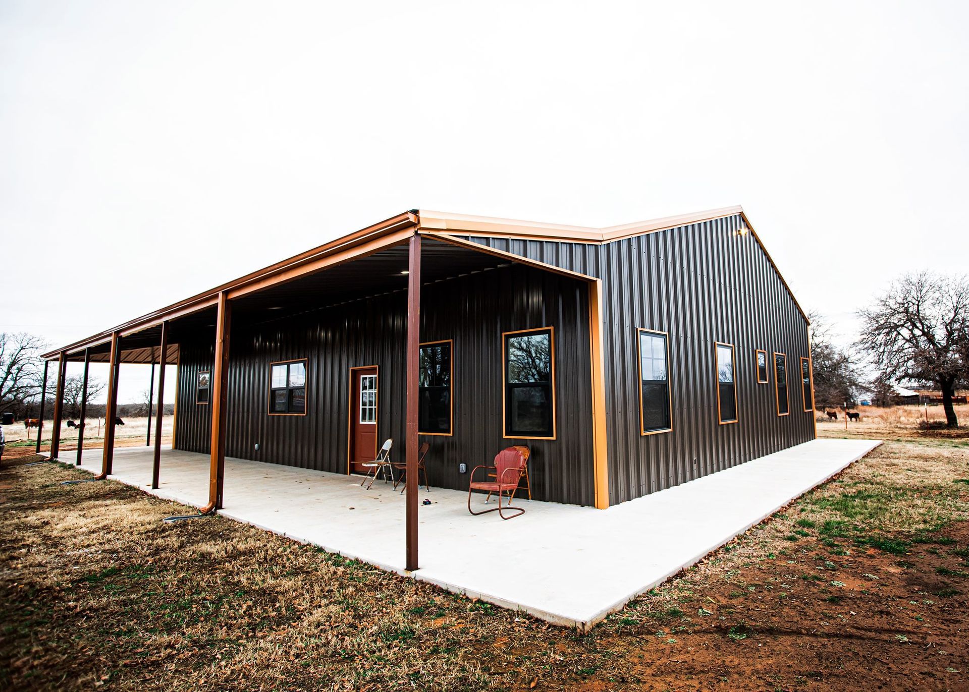A large metal building with a porch and chairs in front of it.