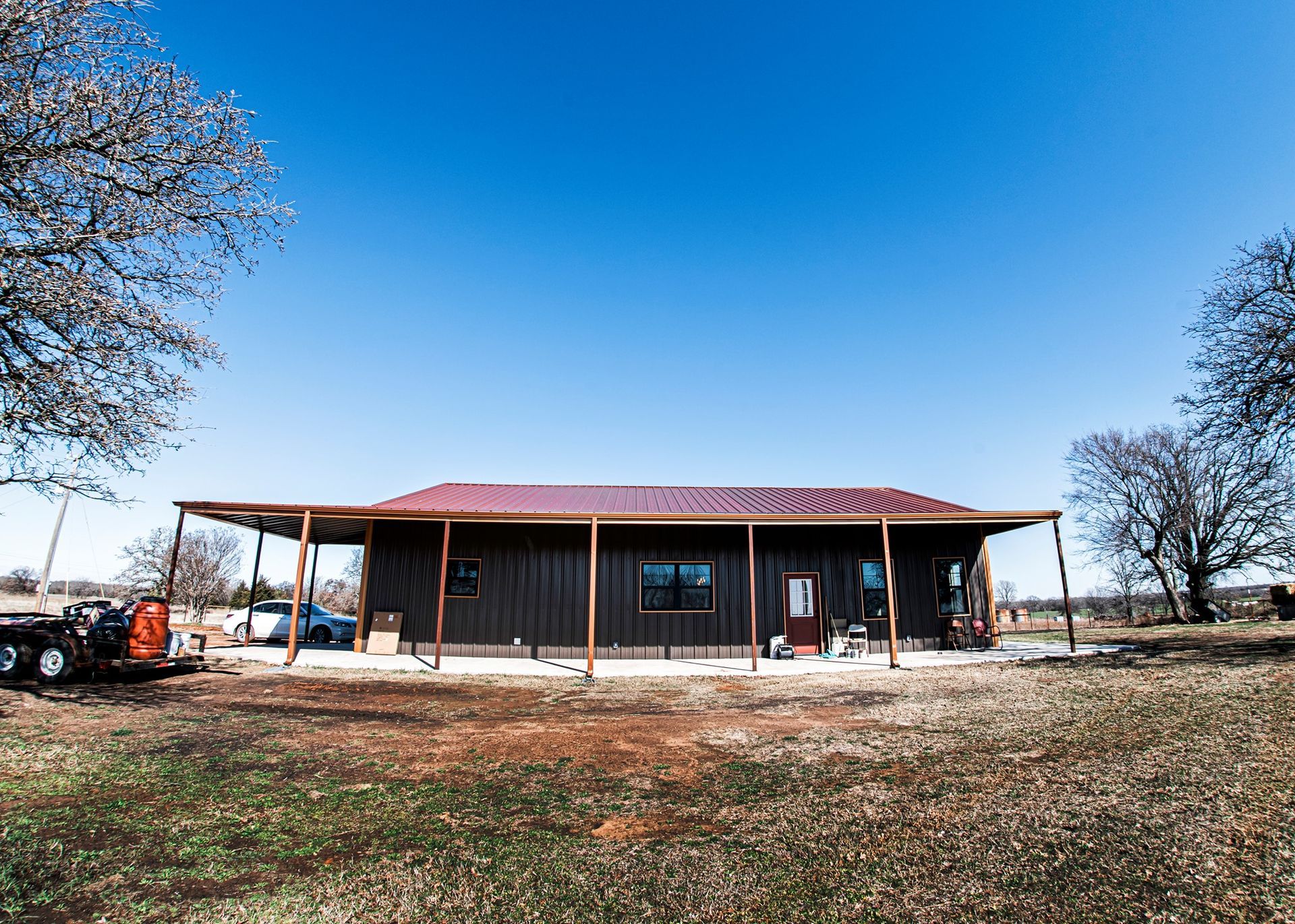 A large house with a red roof is sitting in the middle of a field.