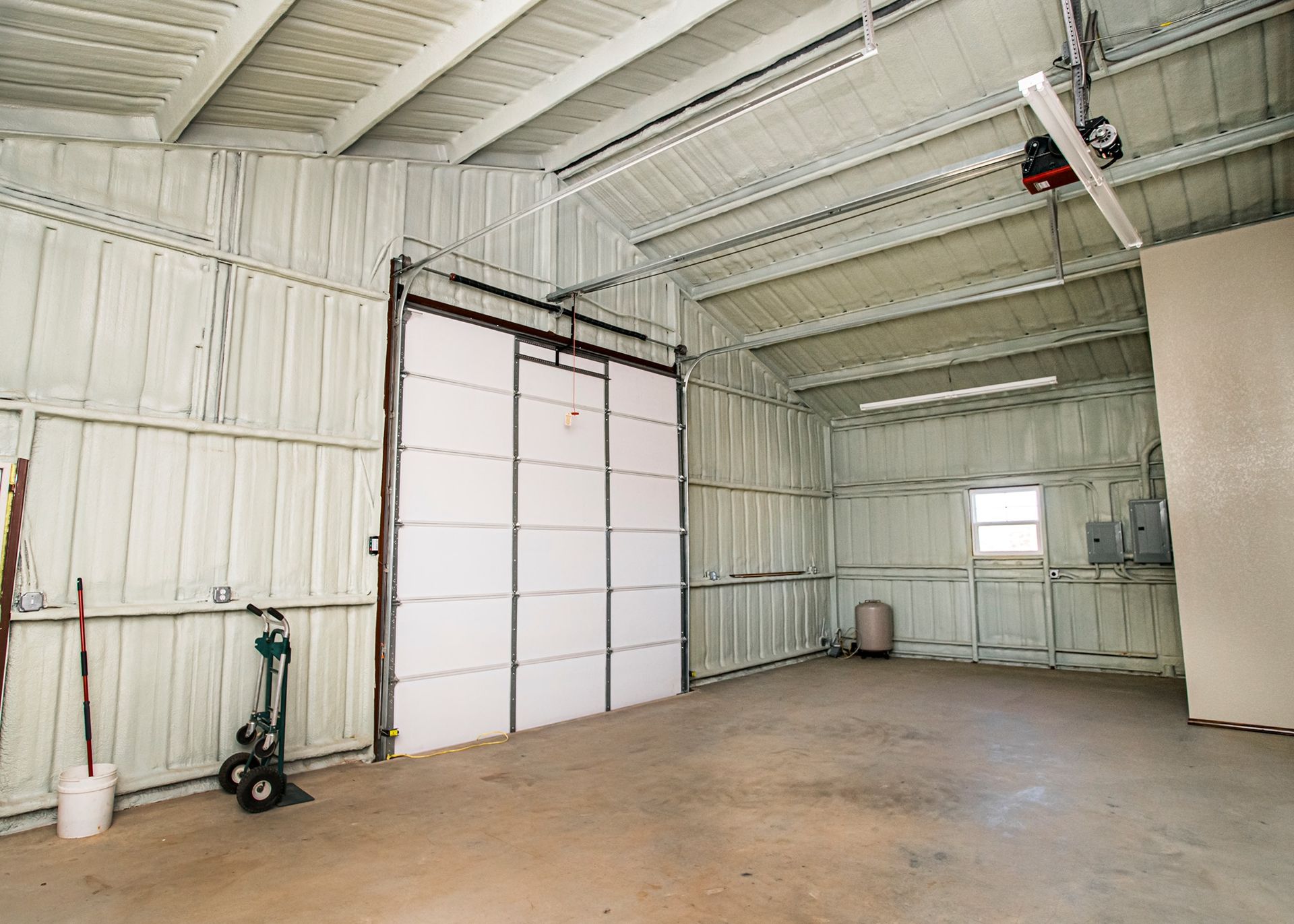 An empty garage with a sliding garage door and a window.