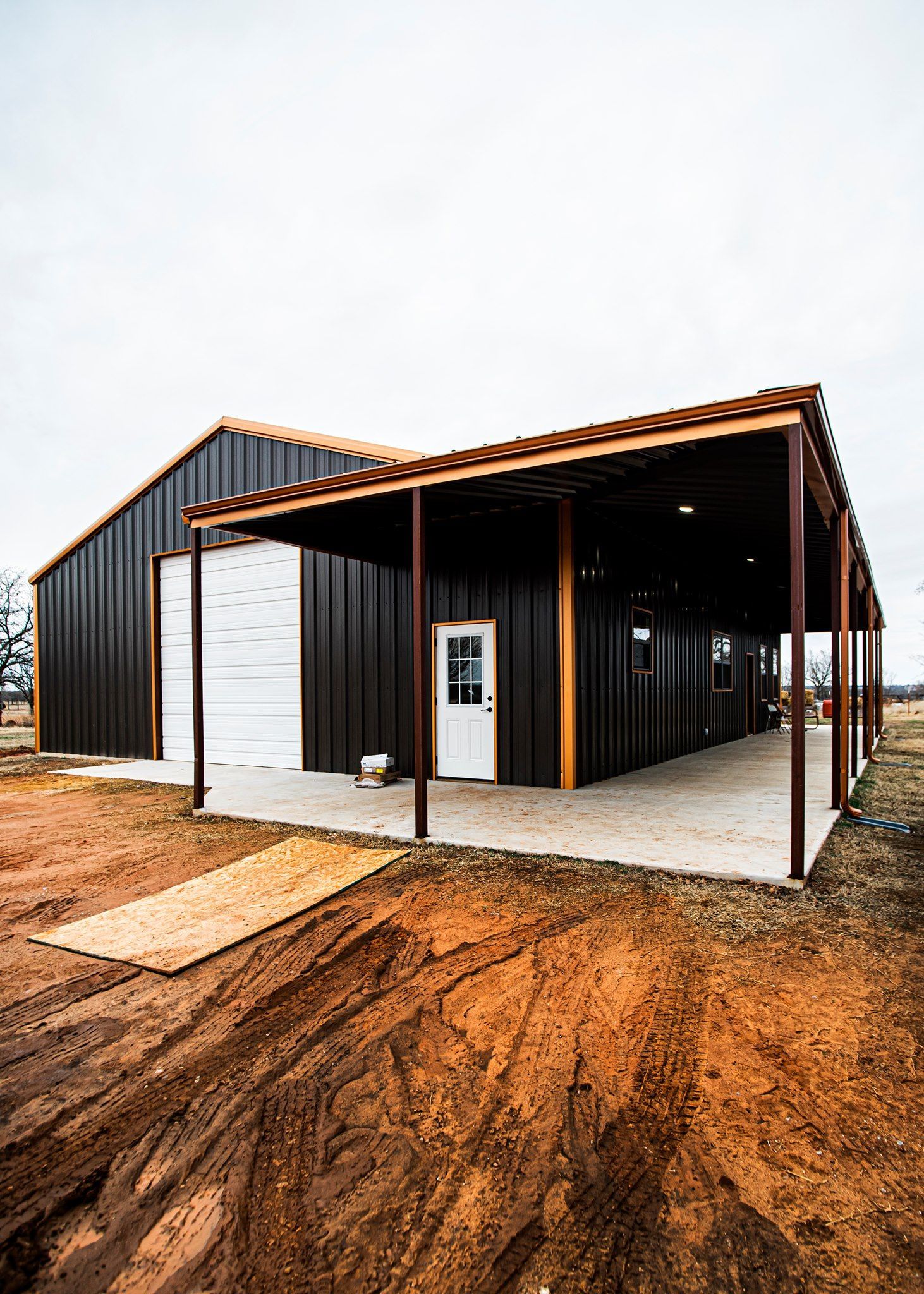 A black metal building with a white door and a covered porch.