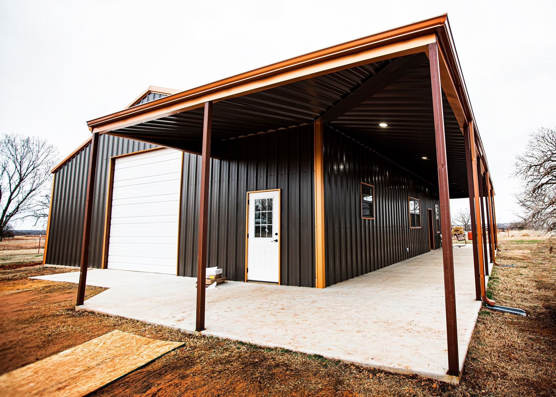 A large metal building with a porch and a garage door.