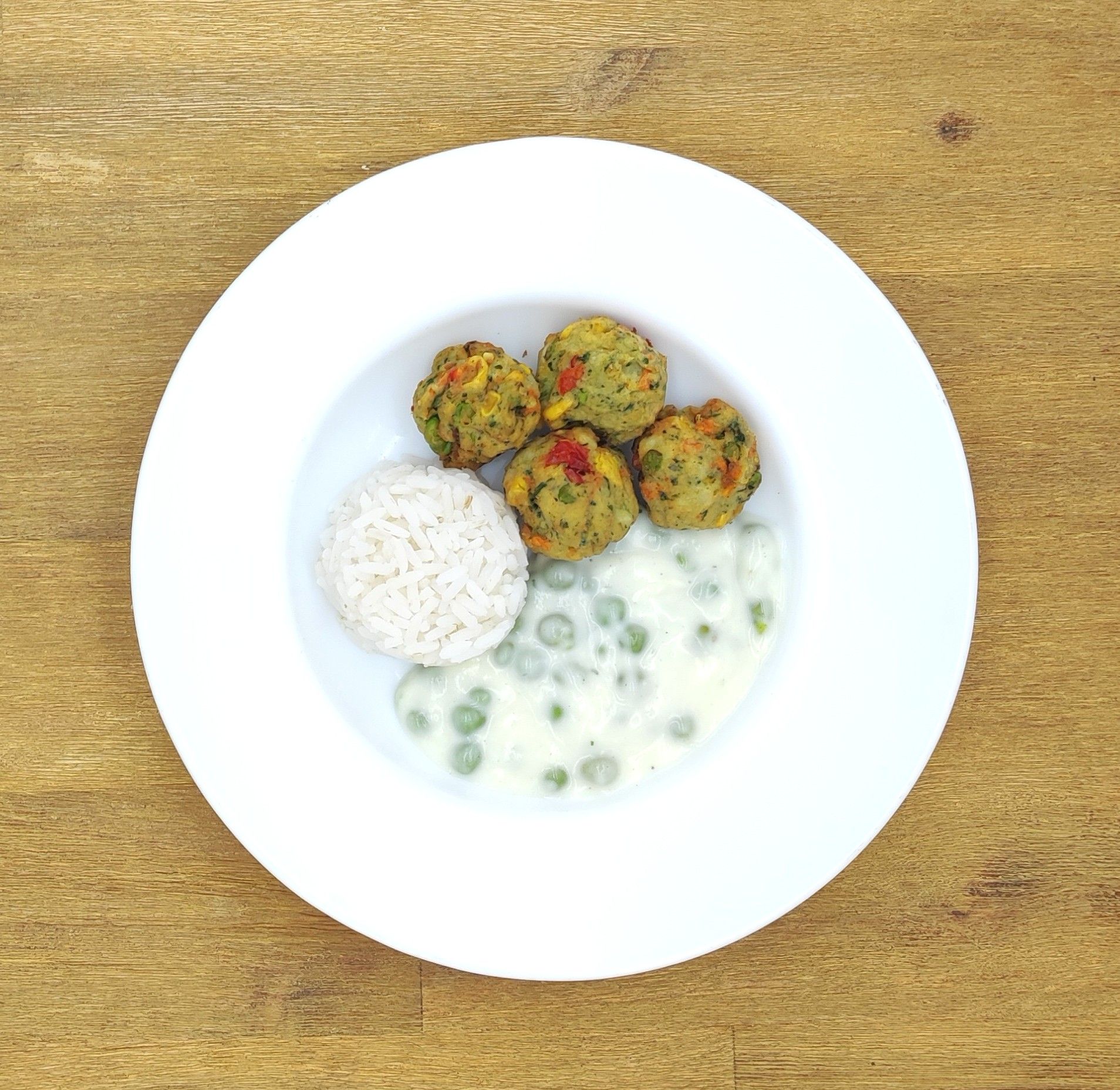 Eine grüne Plüschraupe mit Kochmütze hält einen Löffel über einem Teller mit der grünen Aufschrift „Bild folgt“.