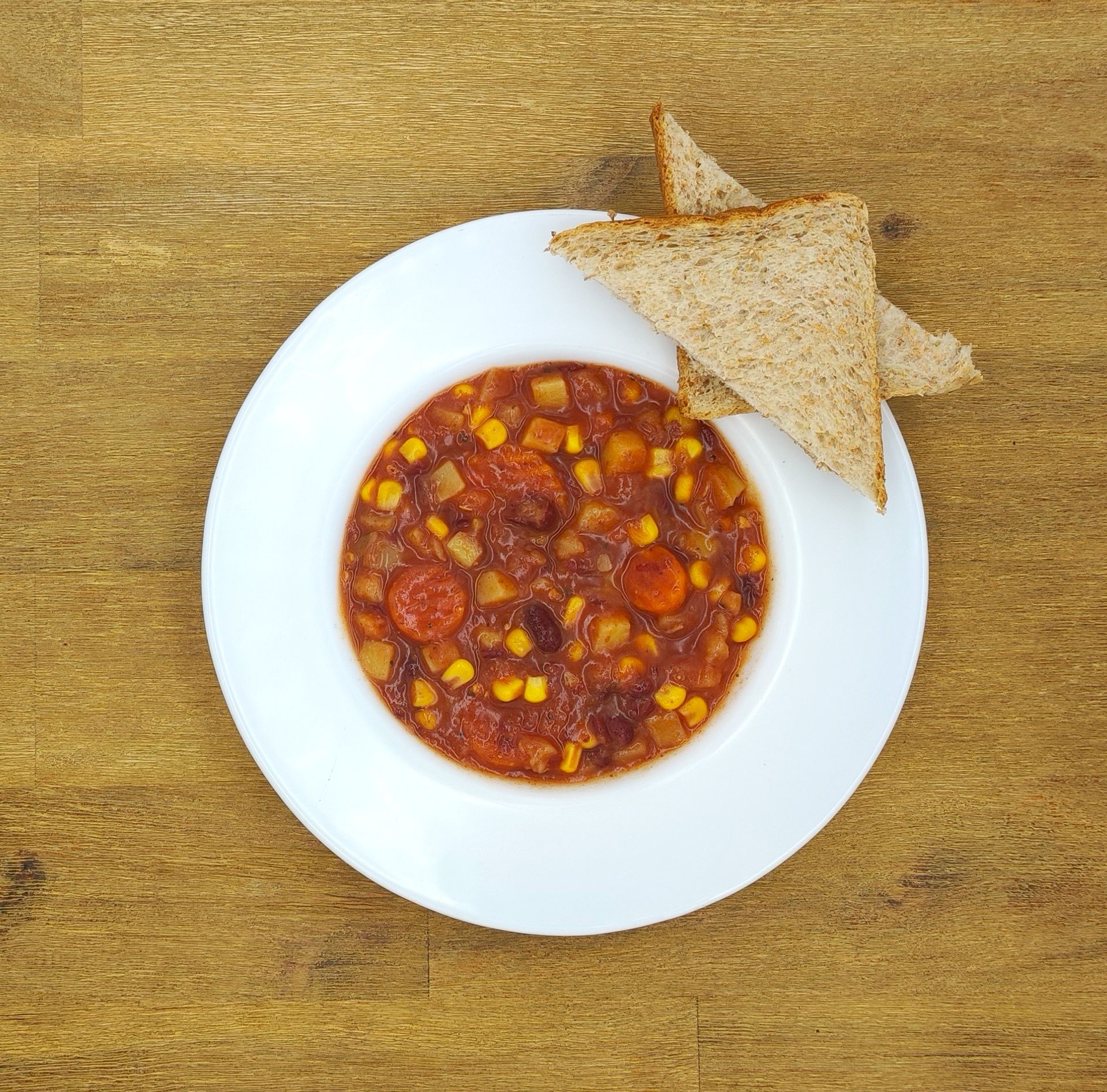 Eine Schüssel Chili mit Mais und Bohnen, serviert mit geröstetem Brot.